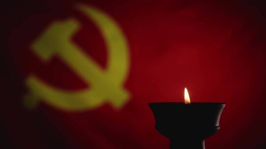 蜡烛烛光映照下鲜艳的红色中国共产党党旗