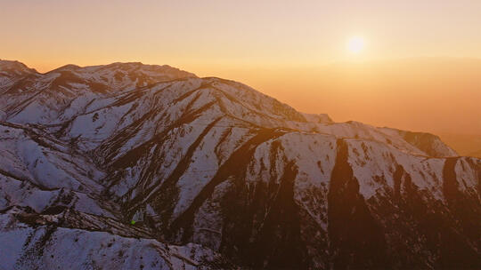 日落时分金黄色的雪山山峰晚霞峡谷航拍