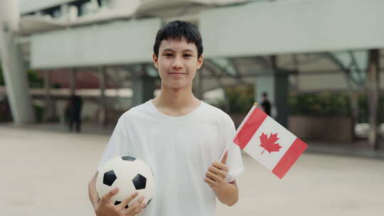 亚洲青少年足球迷在户外与加拿大国旗和球合
