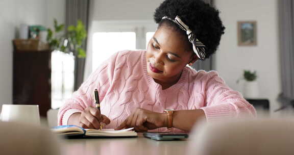 非裔美国妇女在家里的笔记本上写字