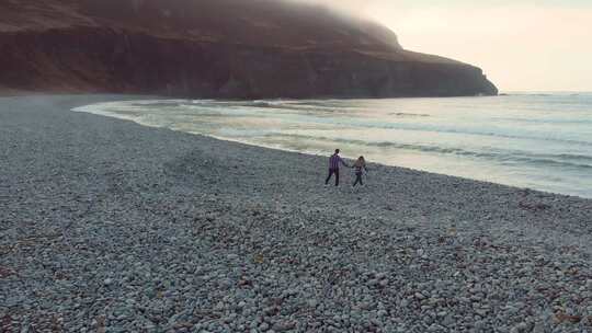 爱尔兰年轻夫妇手拉手走向大海