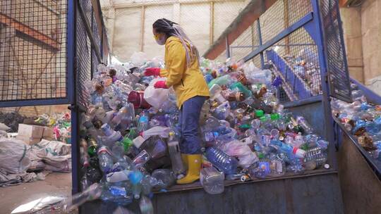 女子在回收工厂用手舀用过的瓶子的镜头