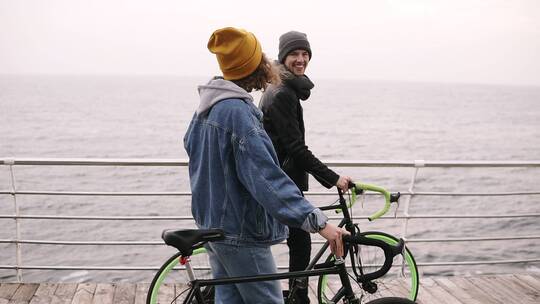 情侣推着自行车在海边漫步