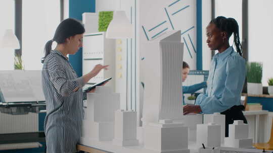 女性在建筑事务所使用数字平板设计城市建筑模型视频素材模板下载