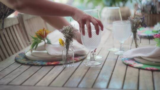 女人摆放桌子上的酒杯和花束