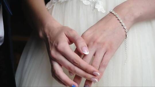 新娘双手放在膝盖左手戴着漂亮的珍珠手镯