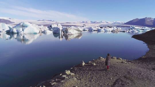 一名妇女站在北极冰川泻湖岸边