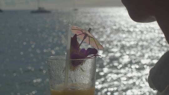 女人在海边喝橙汁