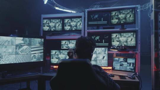黑客在监控室观看安全摄像头视频素材模板下载