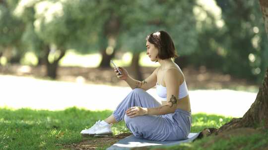 一个女人手里拿着手机坐在草地上