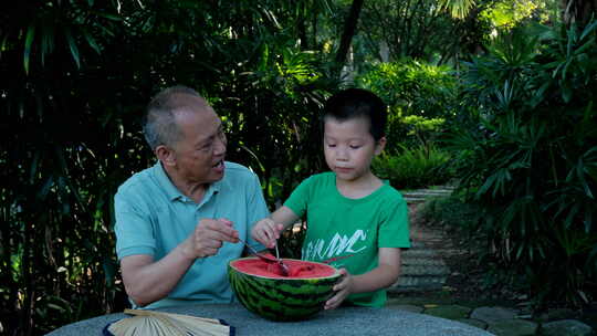 炎热夏天树下乘凉 老爷爷和孙子一起吃西瓜视频素材模板下载
