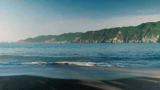 海边沙滩海浪及远处的青山风景