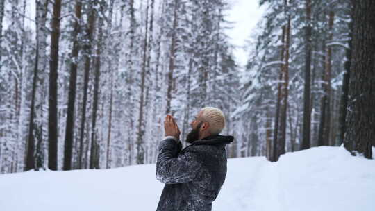 童话般的冬季森林里快乐的年轻人跪着向上帝