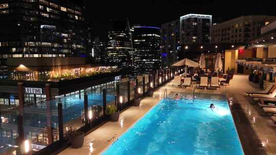 美女帅哥情侣在度假酒店楼顶游泳池游泳