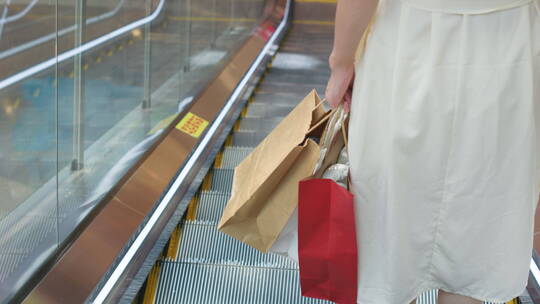 中国女性在商场购物手拎购物袋步行