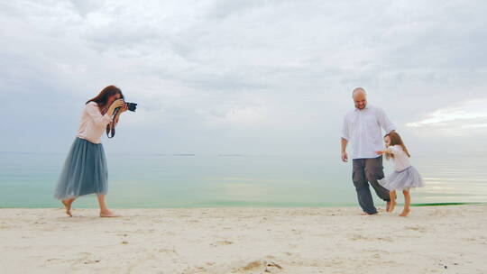 妈妈在海滩帮女儿和爸爸拍照