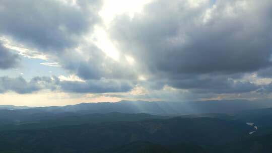 航拍群山间阳光穿透云层的壮阔自然景观