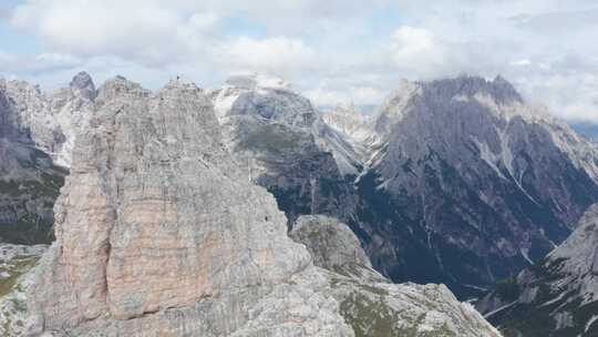 徒步旅行者站在多洛米蒂崎岖的托雷迪托布林山顶；无人机视差