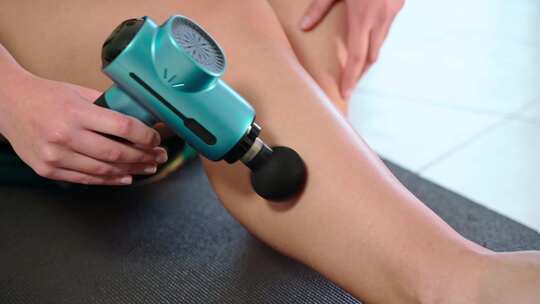 一名女运动员使用现代按摩枪进行小腿治疗性放松高清在线视频素材下载