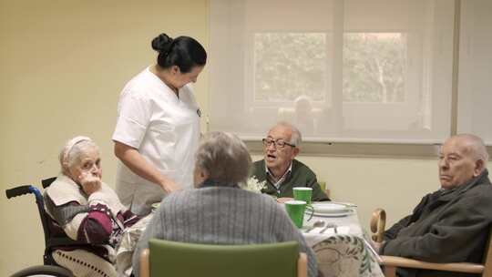 护理员在疗养院食堂与老人交谈