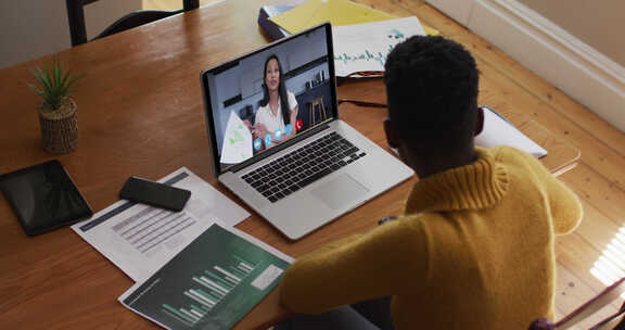 非裔美国妇女使用笔记本电脑与在家工作的女同事进行视频通话