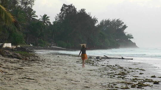 女人挥舞着手臂沿着海滩行走