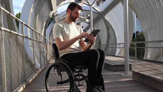 轮椅上专注的人在建筑桥梁上使用平板电脑视频素材模板下载