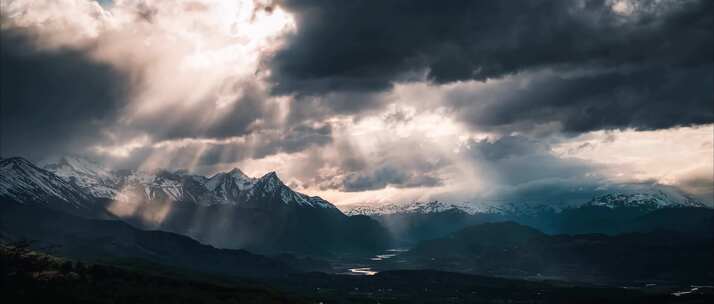 阳光穿过云层照射在高原雪山上耶稣光延时