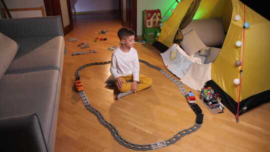男孩坐在家里房间的地板上玩玩具铁路