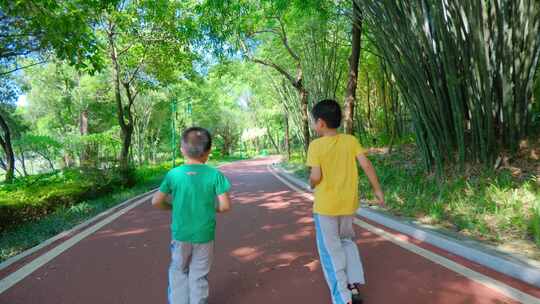 两个小孩在公园跑道跑 林荫小路 向前冲