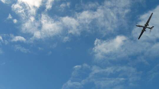 军用无人机在阳光明媚的日子里飞过天空。超