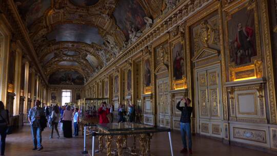 游客们走在巴黎卢浮宫博物馆的内部画廊里
