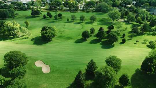 白天，无人机在被郁郁葱葱的绿色植被和小池塘覆盖的高尔夫俱乐部上空飞行。