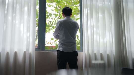 男子窗边思考背影