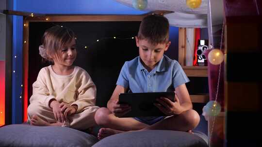 儿童在儿童之家小屋的平板电脑上观看有趣的