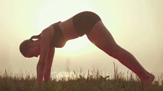 女人在日落夕阳下做瑜伽拉伸运动