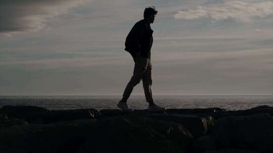 男孩早上在海里的岩石上散步视频素材模板下载