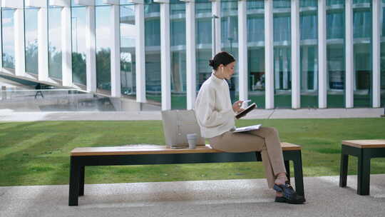 现代办公室附近笔记本电脑坐凳上的女性聆听在线网络研讨会