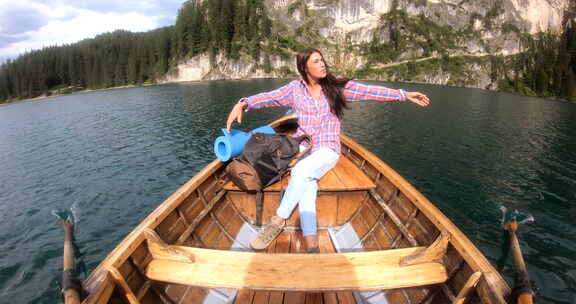 一个男人划着木船在湖中央划船，看着他的妻