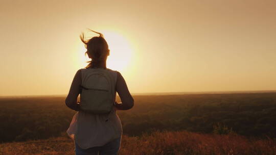 一个背着背包的年轻女人朝着太阳跑去