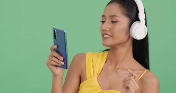 女孩拿着手机戴着耳机享受音乐