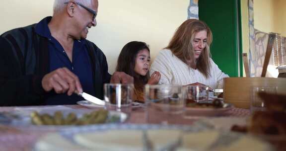 快乐的拉丁女孩在家和祖父母一起吃饭很开心
