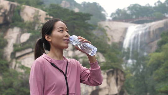 亚洲中国人女性在瀑布下喝水饮用水