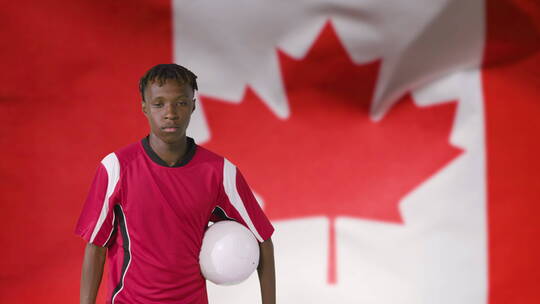 加拿大国旗前抱着足球的男人