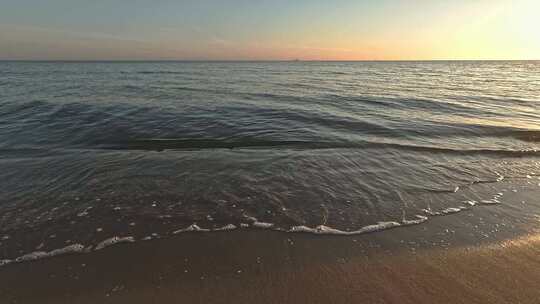 平静的水——早上6点左右日出时海滩上的海浪——特写。波罗的海。