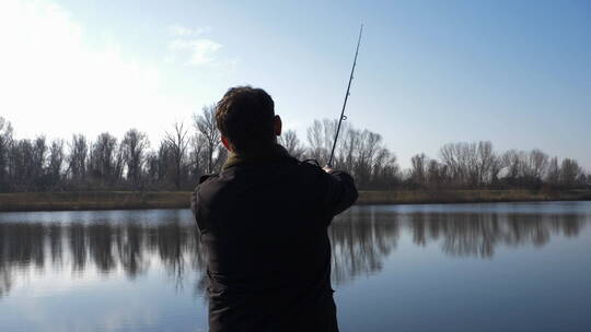 男人站在湖边钓鱼