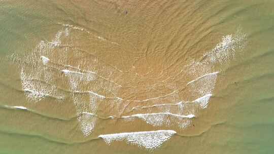 航拍俯瞰山东威海国际海水浴场沙滩上的海浪