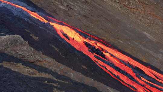 熔岩流从岩石柱中出现，涌入黑色火山景观—