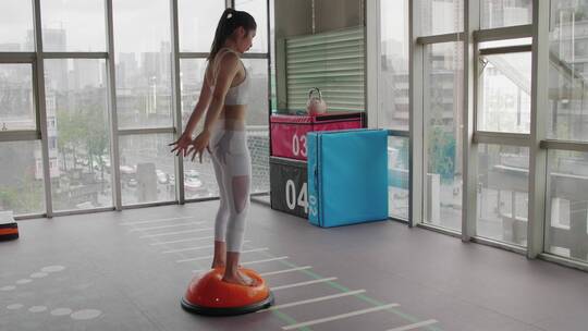 一位女青年在健身房锻炼身体下蹲运动