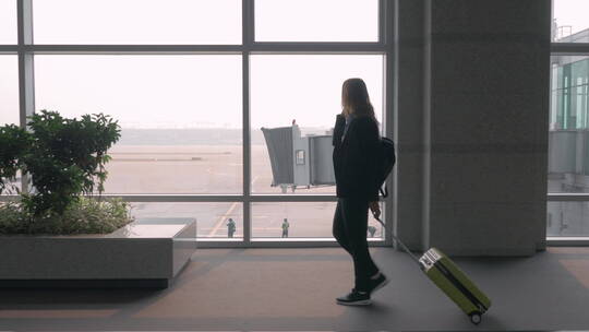 女子在机场航站楼拉行李箱打电话视频素材模板下载